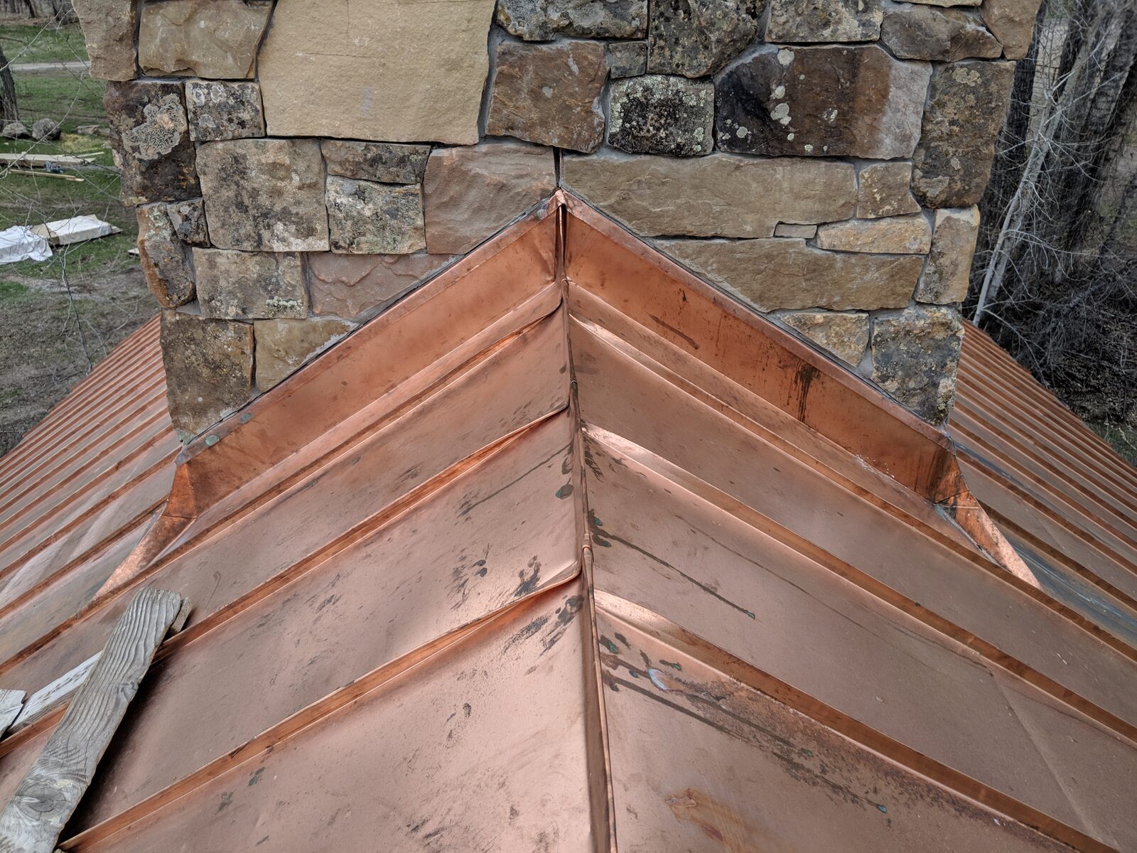 Soldered copper ridge and valley work meeting natural stone