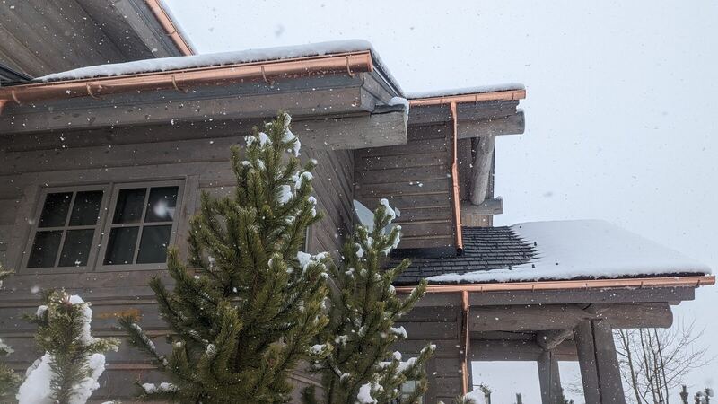 Copper gutter and downspout detail in falling snow
